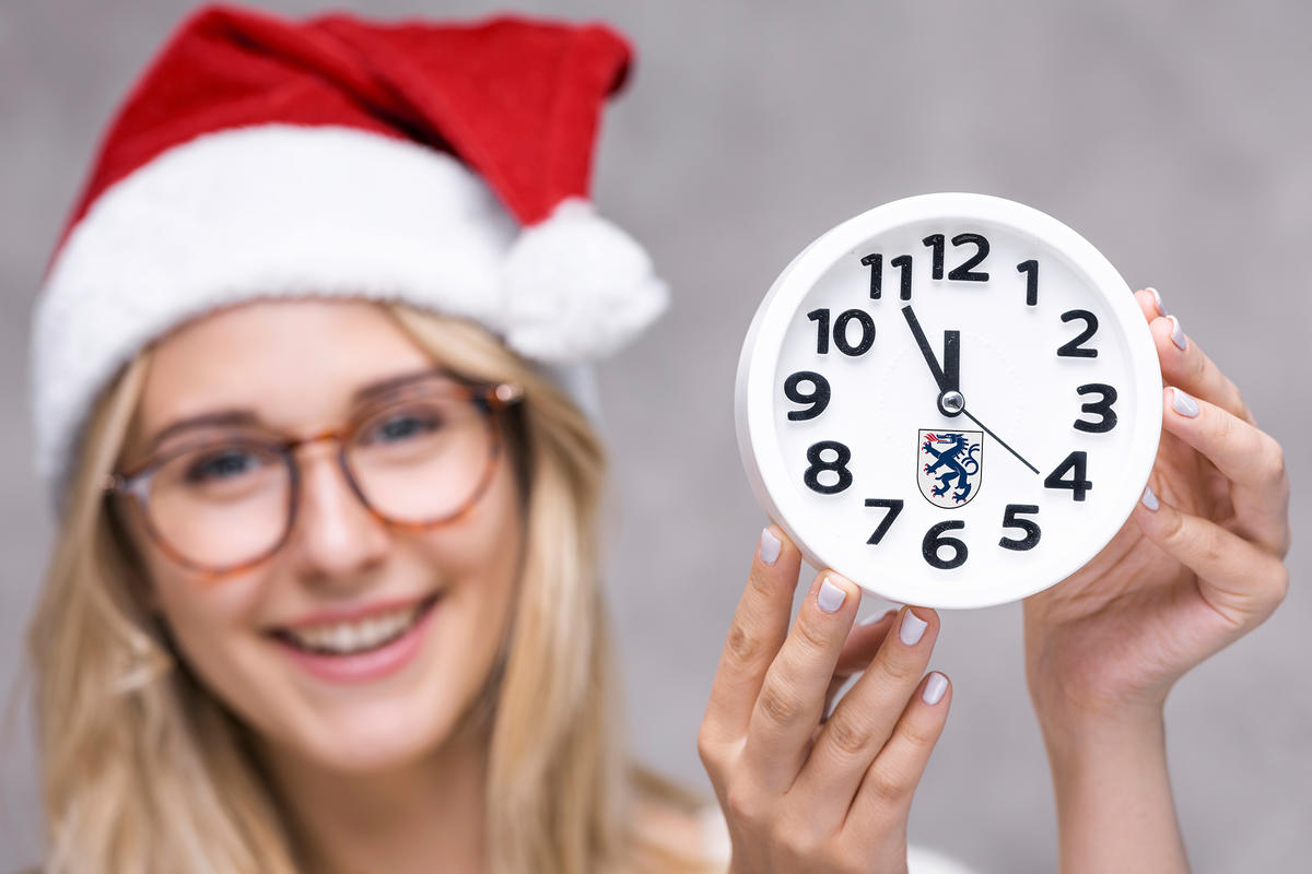 Öffnungszeiten - Themenbild Frau mit Weihnachtsmütze und Uhr