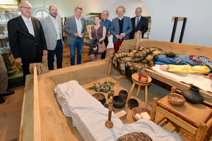 Bild vergrößern: Stadtarchäologe Dr. Gerd Riedel (rechts) und Kulturreferent Gabriel Engert (2.v.r.) präsentierten die Rekonstruktion des Kammergrabs im Stadtmuseum